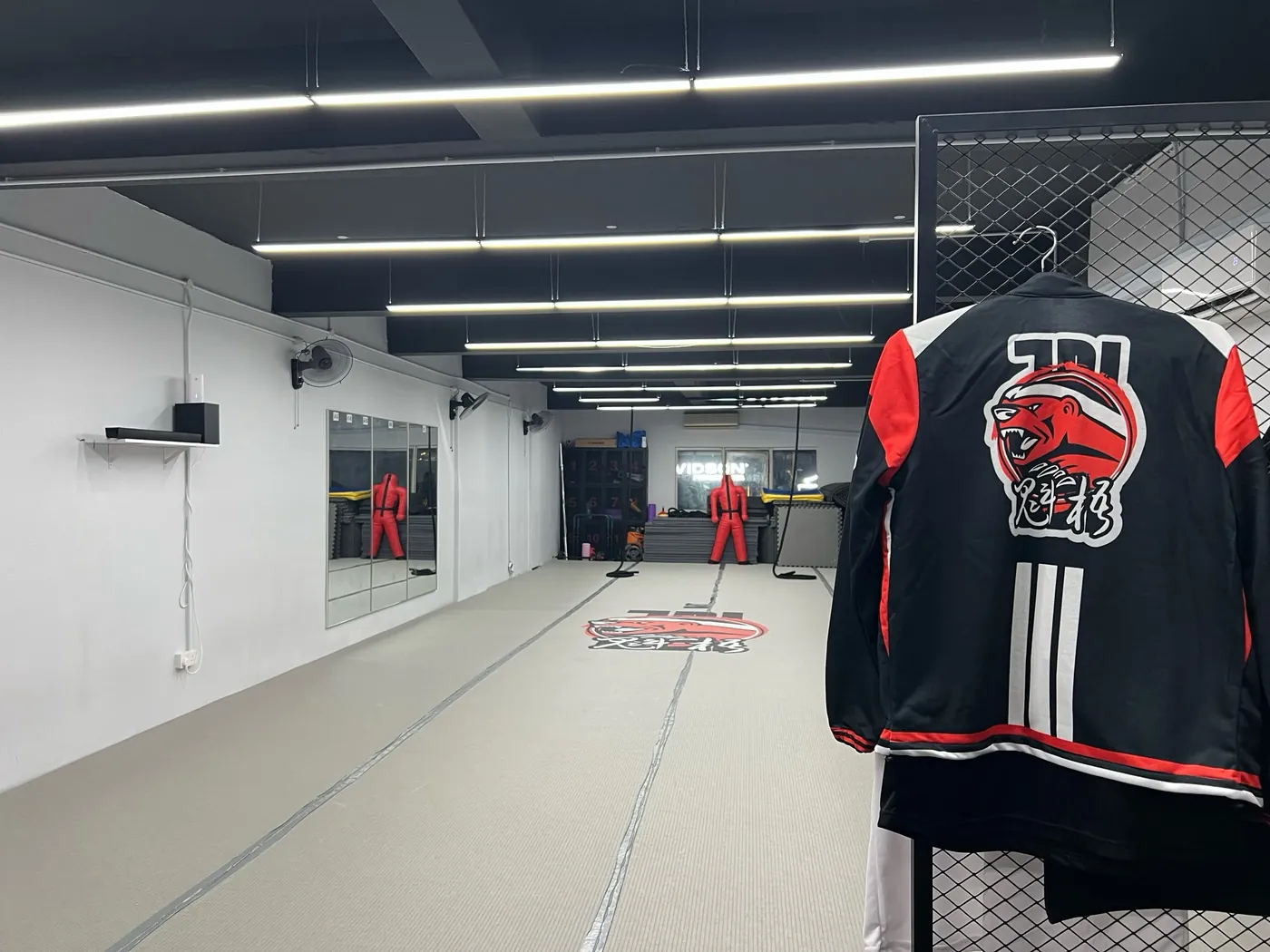 JDI team jacket in black, red and white hanging beside the mat